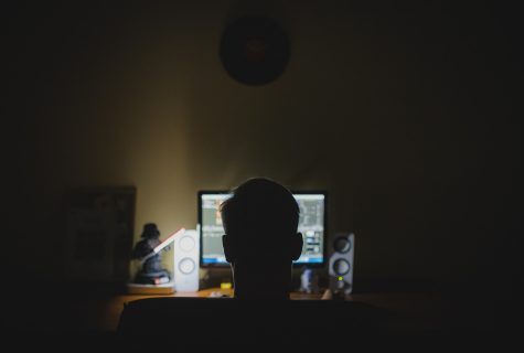 man in the dark illuminated by computer light